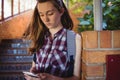 Attentive schoolgirl using mobile phone near staircase