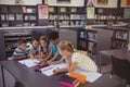 Attentive schoolkid using digital tablet in library