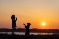 A girl in a jacket trains a guard dog of the Rottweiler breed against the backdrop of a lake and sunset Royalty Free Stock Photo