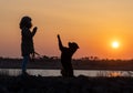 A girl in a jacket trains a guard dog of the Rottweiler breed against the backdrop of a lake and sunset Royalty Free Stock Photo