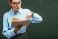 Attentive teacher in eyeglasses pointing with