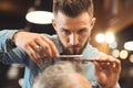 Attentive young barber working in the barbershop