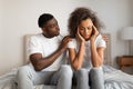 Attentive young black husband comforting his upset wife in bedroom Royalty Free Stock Photo