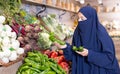 Attentive young Muslim woman purchaser choosing peppers in grocery store Royalty Free Stock Photo