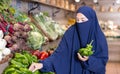 Attentive young Muslim woman purchaser choosing peppers in grocery store Royalty Free Stock Photo