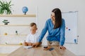 Attentive young woman tutor teacher helping little boy pupil with studying, correct mistakes explain learning material. Smiling