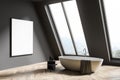 Attic gray bathroom interior with tub and poster Royalty Free Stock Photo