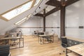 Attic office open space with beams, glass doors, brick wall, wooden floor, furniture and computers.