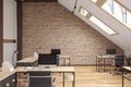 Attic office open space with beams, glass doors, brick wall, wooden floor, furniture and computers. Royalty Free Stock Photo