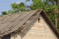 Attic of an old brown brick house with a small window and a broken gray slate roof on a rural street Royalty Free Stock Photo