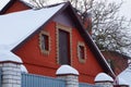 Attic of a red country barn with a door and windows and white snow on the roof behind the fence Royalty Free Stock Photo