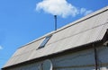 Attic skylight roof window on the asbestos house roof with blue sky background