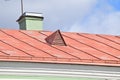 Attic window with decorative lattice. Red tin roof. Green duct pipe Royalty Free Stock Photo