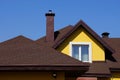 Attic of a yellow house with a window and a brown tiled roof against the sky Royalty Free Stock Photo