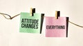 ATTITUDE CHANGES EVERYTHING text words inscription on yellow sticker note on white wall or table