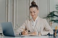 Attracative successful businesswoman in elegant suit making to do list at work