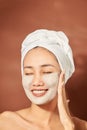 Attracitve young Asian woman applying clay mask on her facee. Spa and wellness, skin care product concept