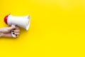 Attract attention concept. Megaphone in hand on yellow background top view copy space Royalty Free Stock Photo