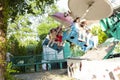 Adults and children ride carousels in the park. Attractions for the whole family.