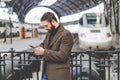 Attractive adult man using mobile application on his smartphone at train station.Business travel concept. Royalty Free Stock Photo