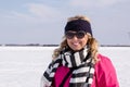 Attractive adult woman poses in farm field covered in snow on a sunny day in winter