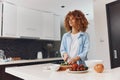 Attractive African American female cooking healthy salad in modern home kitchen interior with fresh vegetables Royalty Free Stock Photo
