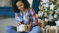 Attractive mixed race girl packing gift box near Christmas tree at home Royalty Free Stock Photo