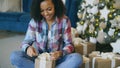Attractive mixed race girl packing gift box near Christmas tree at home Royalty Free Stock Photo