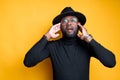 Attractive african american man in glasses in a hat touches his head with his hands and opens his mouth Royalty Free Stock Photo