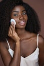 Beautiful happy black girl purifying skin with cotton pad. Skincare concept.