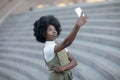 Attractive african american woman taking a picture of herself with her camera phone on a amphitheatre stairs Royalty Free Stock Photo
