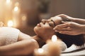 Attractive african girl enjoying face massage in spa salon.