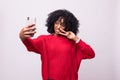 Attractive african woman with afro taking a picture of herself with her camera phone isolated on white background Royalty Free Stock Photo
