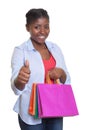 Attractive african woman with shopping bags showing thumb