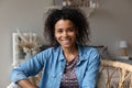 Attractive African woman sit on armchair looking at camera