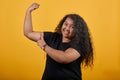 Attractive afro-american woman showing muscules, pointing finger on it, smiling