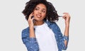 Attractive American African woman in white t-shirt and blue denim shrit, talking on smart phone to her friend, looking cheerful,