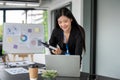 An attractive Asian businesswoman bending over a table and using her laptop computer Royalty Free Stock Photo