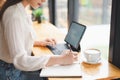 An attractive asian businesswoman in the cafe, using tablet and note on booklet. Soft focus