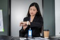 An attractive Asian businesswoman checking time on her wristwatch while sitting at her desk Royalty Free Stock Photo