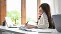 Attractive asian businesswoman or female secretary talking on the phone at desk Royalty Free Stock Photo