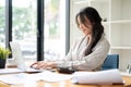 An attractive Asian businesswoman is focusing on her work on a laptop at her desk Royalty Free Stock Photo