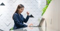 An attractive Asian businesswoman girl expressing a winning moment. Worker working on laptop at the office showing her confidence Royalty Free Stock Photo