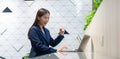 An attractive Asian businesswoman girl expressing a winning moment. Worker working on laptop at the office showing her confidence Royalty Free Stock Photo