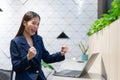 An attractive Asian businesswoman girl expressing a winning moment. Worker working on laptop at the office showing her confidence Royalty Free Stock Photo
