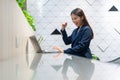 An attractive Asian businesswoman girl expressing a winning moment. Worker working on laptop at the office showing her confidence Royalty Free Stock Photo