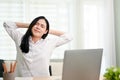 Attractive Asian businesswoman hands behind her head, eyes closed, relaxing at her desk Royalty Free Stock Photo