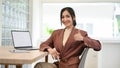 Attractive Asian businesswoman at her desk showing thumb up sign. great job, awesome Royalty Free Stock Photo