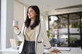 Attractive Asian businesswoman in her office daydreaming while sipping coffee Royalty Free Stock Photo