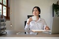 An attractive Asian businesswoman sipping coffee while working on her work at her desk Royalty Free Stock Photo